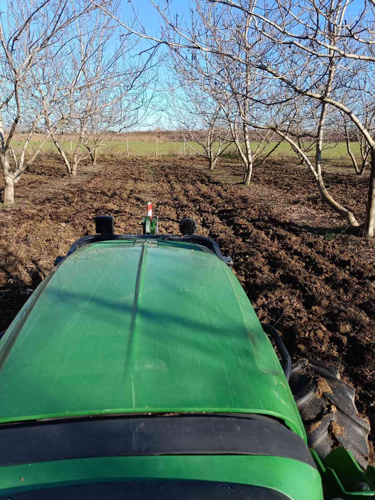 Τρακτέρ John Deere σε όργωμα εδάφους σε οπωρώνα τον χειμώνα